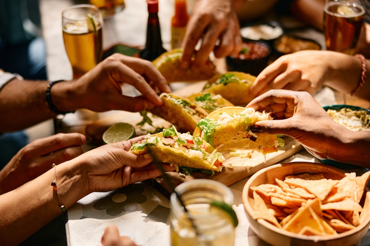 Hands reaching for tacos and nachos.